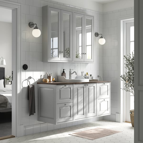 Modern bathroom with grey TÄNNFORSEN vanity, mirror cabinets, & natural light.