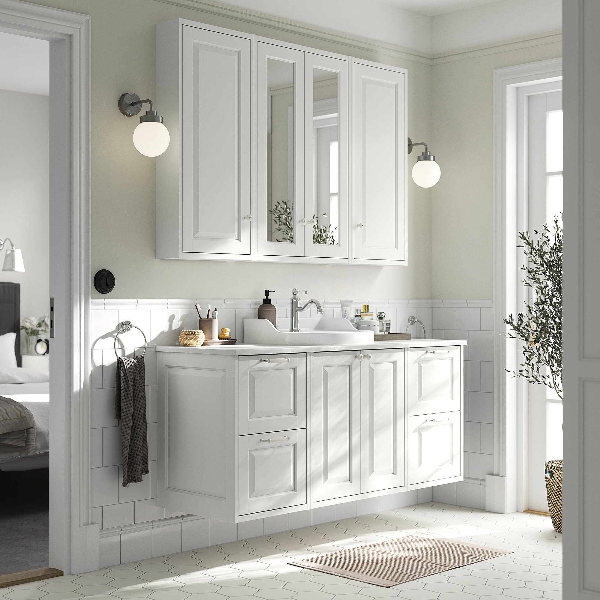 White bathroom vanity with two drawers, two doors, and a sink. Mirrors above, wall-mounted lights, gray towels, and a rug.