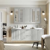 Spacious gray bathroom vanity unit with double sinks, surrounded by mirrored cabinets and wall lamps.