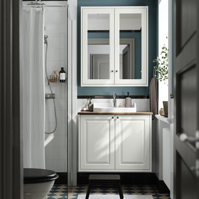 Modern bathroom: TÄNNFORSEN sink, blue walls, checkered floor, black toilet, partial shower, large mirror.