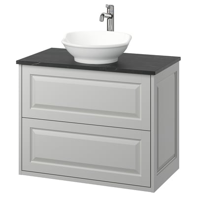 Modern bathroom vanity: light grey cabinet with round white basin & dark countertop.