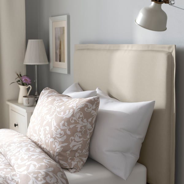 Bed with soft, padded headboard for comfort, patterned pillows, and nightstand with lamp.