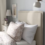 Bed with soft, padded headboard for comfort, patterned pillows, and nightstand with lamp.