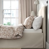Bed with removable, machine-washable cover, padded headboard, and hidden storage under skirt.