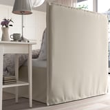 Bed with soft, padded headboard and removable, washable cover. Lamp and decorative items on bedside table.