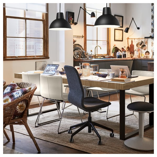 Modern dining area with TARSELE oak veneer table, featuring wire chairs and industrial pendant lights. Computers and accessories on the table.