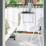 A white tray holds a pitcher and glasses on a balcony table, ideal for serving and fitting most tray racks.