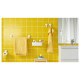 Bright yellow-tiled bathroom with TISKEN white suction hooks holding yellow towels, a soap dish, toothbrushes, and toilet paper.
