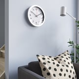 Modern living room with TJALLA clock, white sofa, & floor lamp.