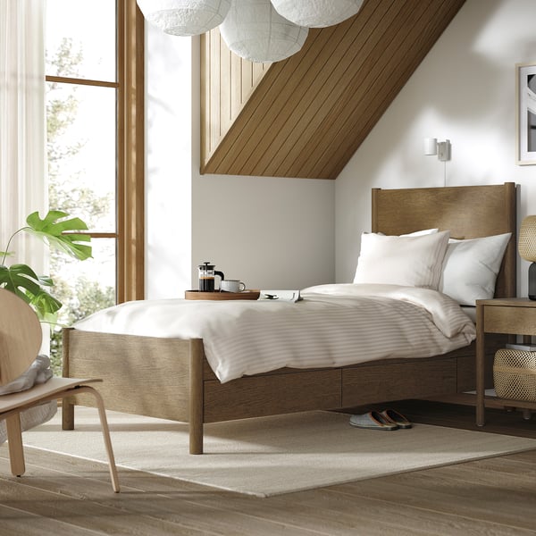 Cozy bedroom with light wood TONSTAD bed, white bedding, soft-close drawers, large window, small rug, and chair.