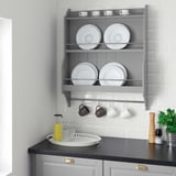 Modern kitchen gray TORNVIKEN wall shelf. Displays white dishes, mugs, and plants. Black counter with gold accents.