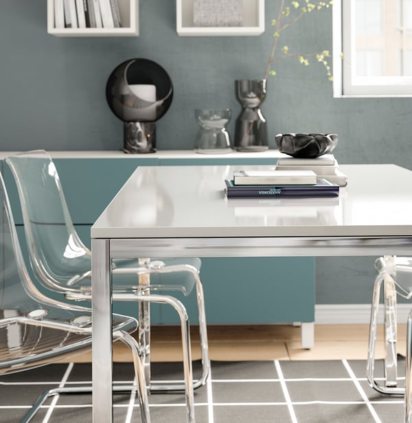 Modern conference table, TORSBY, silver, with high-gloss white top and chrome frame, surrounded by clear chairs.