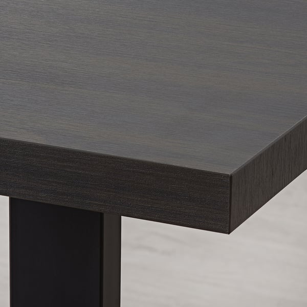 Modern black dining table with sleek, sturdy metal legs and smooth, durable tabletop surface.