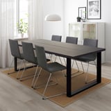 A TRANEBO rectangular dining table with 6 grey chairs on a beige rug, large window, art, pendant light.