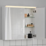 Modern bathroom mirror cabinet with led light and glass shelves, displaying toiletries and cosmetics.
