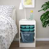 White IKEA TROFAST storage next to bed, with blue/green containers on shelves.