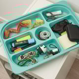 Turquoise TROFAST tray organizes teens items: scissors, masks, keychain, markers, and small toys.