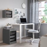 Modern home office with TROFAST storage, laptop, pegboard, grey chair & curtains.