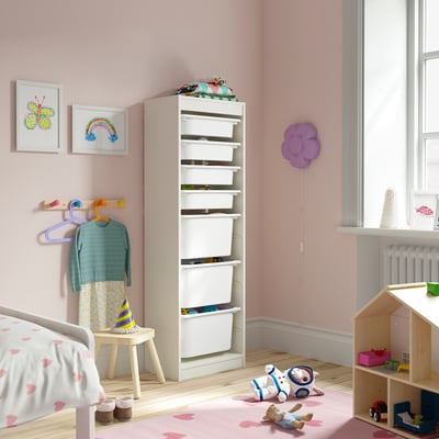 Childs room with TROFAST white storage, pink walls, heart rug, wooden toys, stuffed animals, and colorful art.