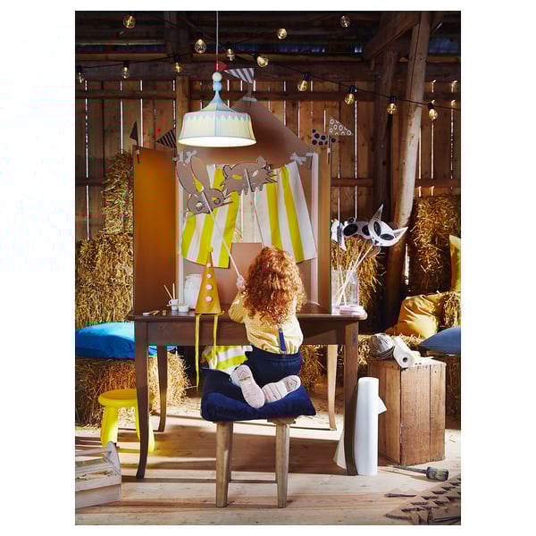 Woman crafts under tent lamp made of recycled plastic in cozy, artistic room.