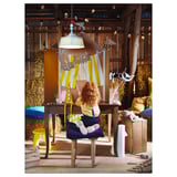Woman crafts under tent lamp made of recycled plastic in cozy, artistic room.