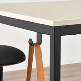 Modern office table with black metal frame, beige top, and hooks for hanging items.