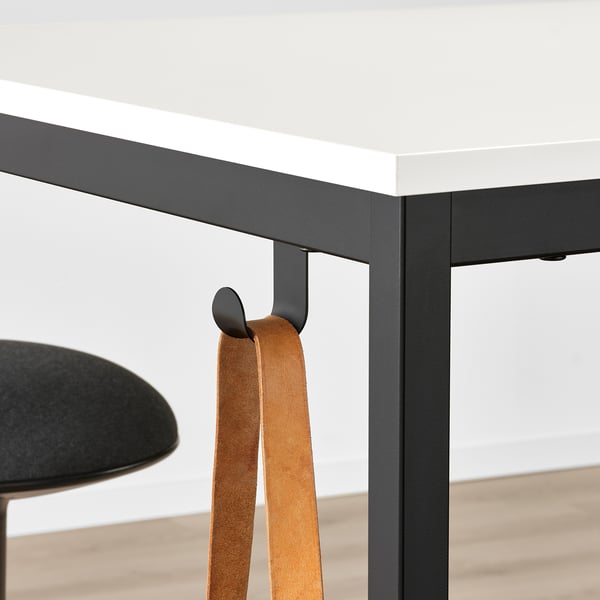 A modern office table with a adjustable footrest and hooks for accessories.