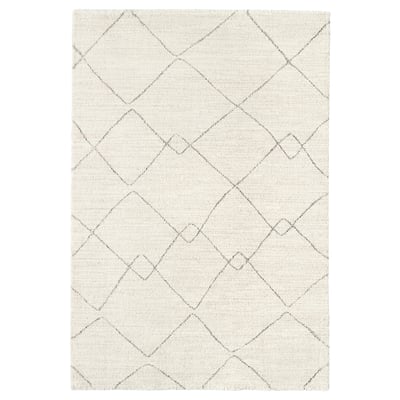 The TVERSTED rug in beige. It a geometric, diamond pattern design with a soft, textured surface, perfect for modern and timeless décor.