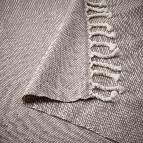 Soft, textured grey wool blanket with fringe detail, folded neatly.
