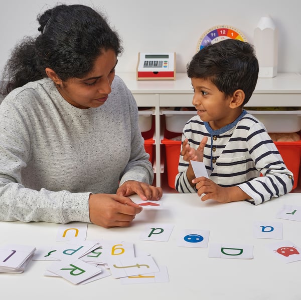 Image description: a woman and child use alphabet cards for learning.