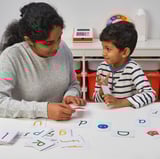 Image description: a woman and child use alphabet cards for learning.