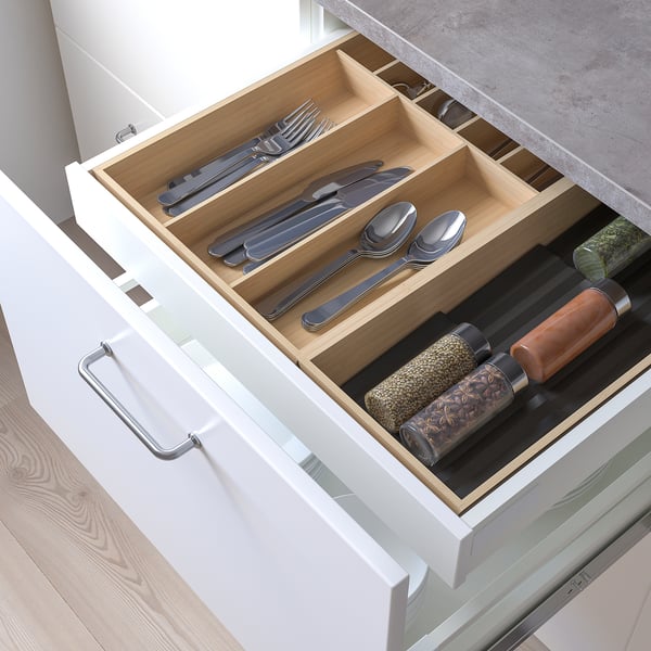 Wooden drawer organizer with metal cutlery and spice jars.