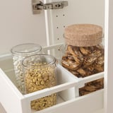 Open kitchen drawer with glass food jars and adjustable dividers.