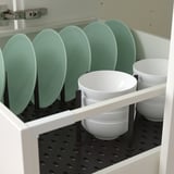 White cabinet with green plates and white bowls organized by adjustable pegs.