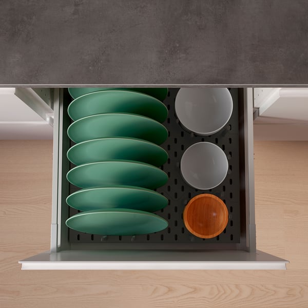 Black drawer organizer with green plates, white bowls, and wooden lid holders; optimizes space and accessibility.