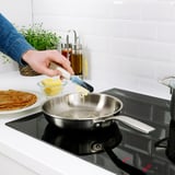 A person grates butter into a pan using a UPPFYLLD tool, demonstrating its versatile kitchen use.