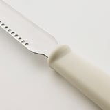 Small stainless steel tool with a white polypropylene handle, designed for spreading butter or icing, with a small curve for precise application.