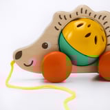 Cute wooden hedgehog toy with bright wheels and yellow string, designed for childrens play.