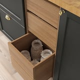 Wooden kitchen drawer with brass handle, partially open, revealing glass jars with contents visible.