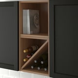 Open kitchen cabinet with wine bottles and cookbooks, part of VADHOLMA storage solutions.