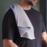Man wearing black shirt with a blue and white patterned cloth draped over shoulder.