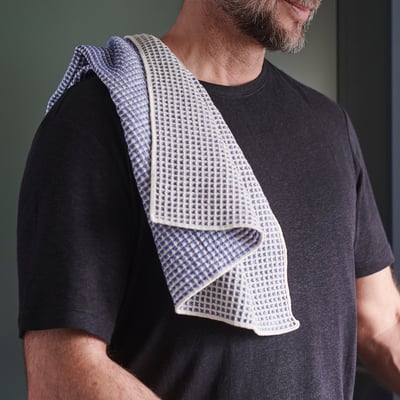 Man wearing black shirt with a blue and white patterned cloth draped over shoulder.