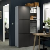 Modern office setup featuring grey storage units with integrated handles, holding books and files, adjacent to a wooden desk with a chair and lamp.