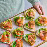 Heart-shaped waffle appetizers topped with smoked salmon, lettuce, and dill. Ready-baked and served on a wooden board.