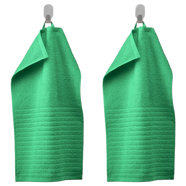 Two green VÅGSJÖN towels hang on silver hooks, bright and absorbent, with a ribbed texture and medium thickness, made of 100% cotton.