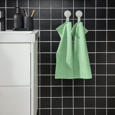 Green towels near sink with toiletries.