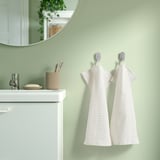 Bathroom with VÅGSJÖN towels on hooks, white cabinet, and mirror.