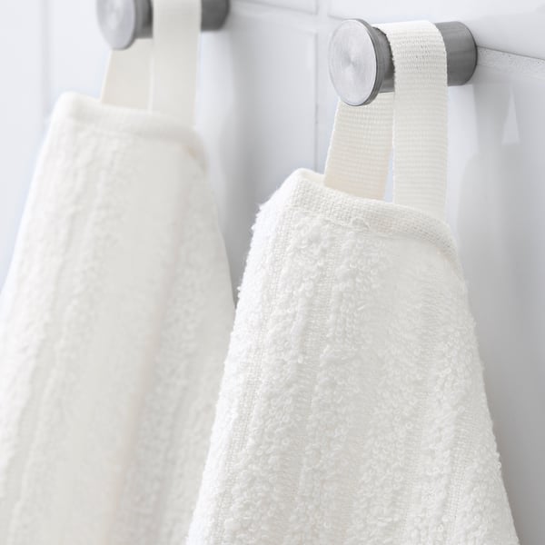 Two white cotton towels hang on metal rings, neatly folded and ready for use.