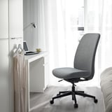 Grey VALLFJÄLLET office chair in minimalist workspace with laptop & lamp.