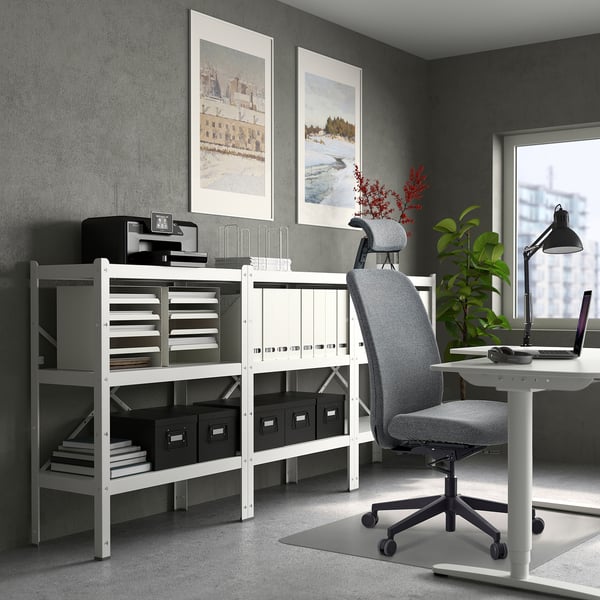 A modern home office setup with a white VALLFJÄLLET office chair, a white desk, and well-organized shelves against a gray wall.